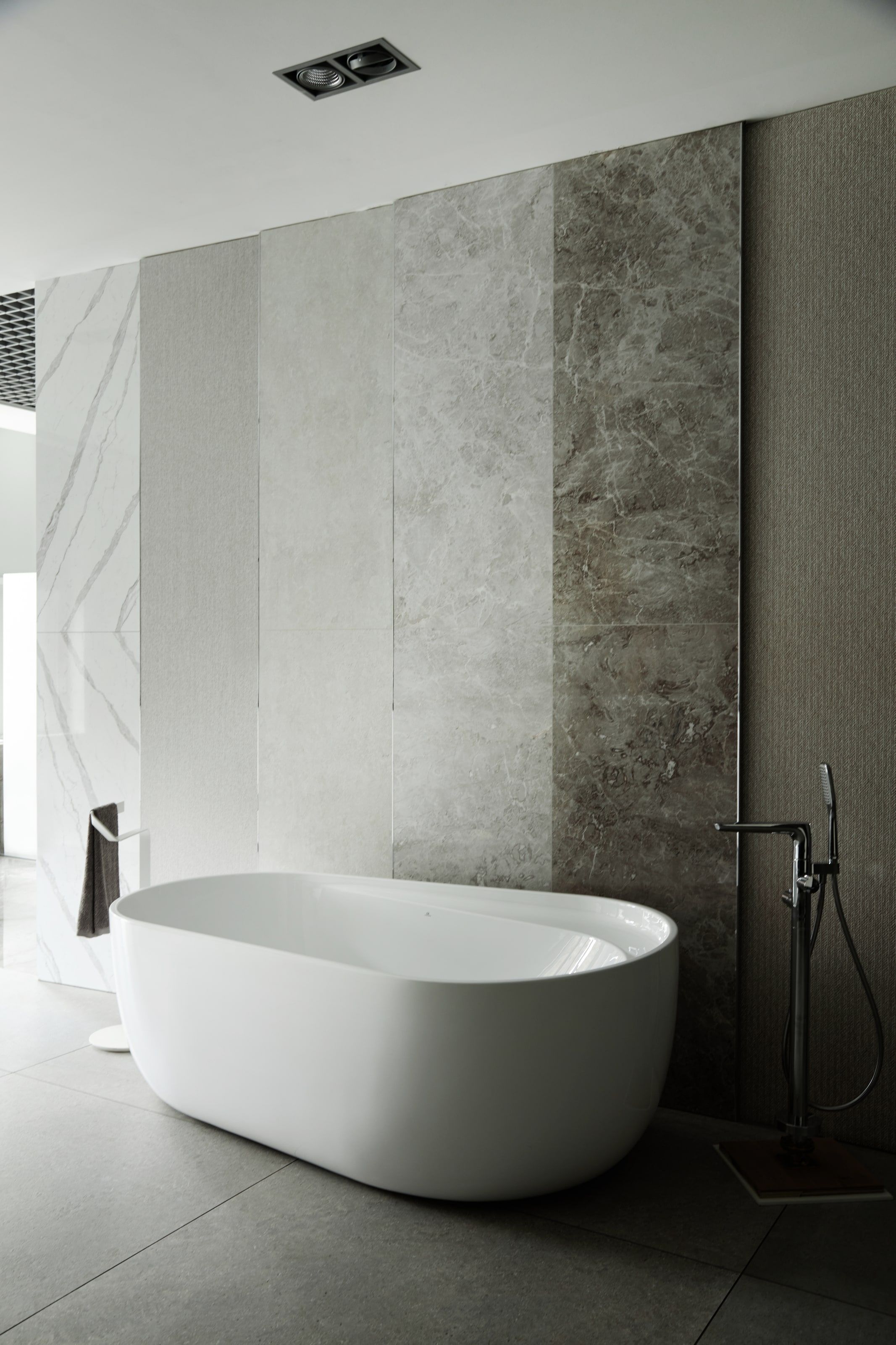 Modernes Bad mit freistehender Wanne vor strukturierter Steinwand